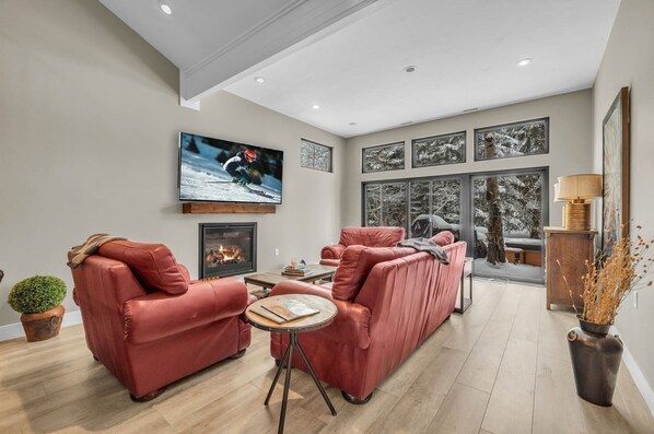 Framed by picture windows with views of Hidden Creek and anchored by a striking stone fireplace, this living room invites you in with plush, leather furnishings, a large flat-screen TV and a coffee table for peak relaxation.