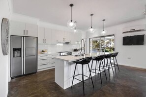 The fully-equpped kitchen boasts generous space with a large central island bench with bar stools for casual dining, stylish pendant lights, wide french door fridge and ample storage.
