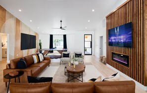 Large and Spacious contemporary living space featuring high ceilings, an electric fireplace, a Smart TV and designer furnishings.