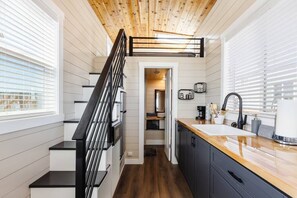 The kitchen is equipped with a refrigerator, freezer, microwave, cooktop, and sink with hot/cold water. Enjoy coffee from the coffee maker and ample counter space. Essentials include cookware, dishes, utensils, and storage cabinets.