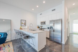 Fully equipped kitchen with stainless steel appliances and barstool seating at the counter.