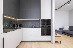A sleek, modern kitchen with black and white cabinets, a built-in oven, and a minimalist design.
