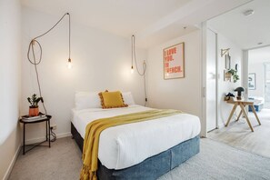 The first bedroom is separated by a sliding door and includes a queen-size bed with hanging lights. 
