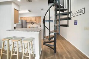 View of kitchen and spiral stairs to the loft. 