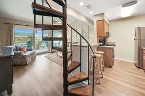 View of the kitchen and living room. There are 5 barstools at the counter.