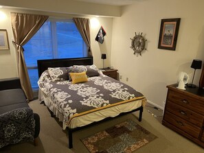 Master bedroom with blackout curtains, futon, dresser space w/ adjacent bathroom