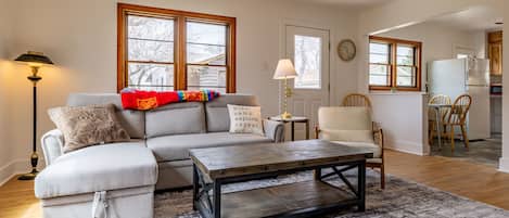 Spacious living room with sleeper sofa, desk, seating and large Smart TV.