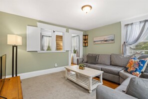 Family room with large L-shaped couch and smart TV, you can see the entrance to the reading room/office