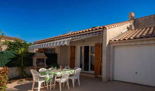Terrace with garden furniture, charcoal barbecue and awning
