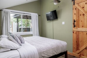 Guest house master bedroom with barn door for privacy, a tv, and large windows for natural light

