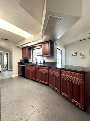 Kitchen features essential appliances. It also has a counter with 2 bar stools.