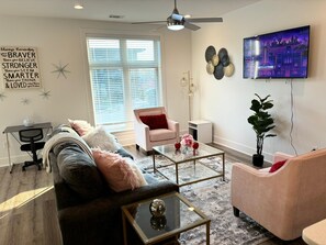 Modern, cozy living room with plush seating, smart TV, and natural light.