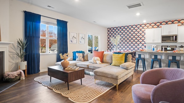 Cozy living area with sectional sofa, patterned accent wall, and a kitchen bar. 