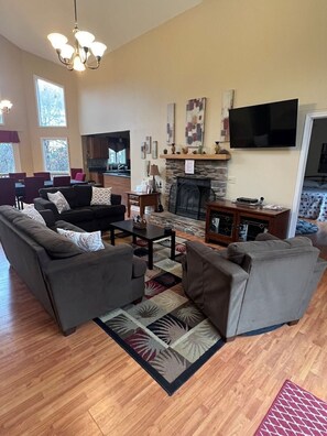 main level living room with wood burning fireplace and flat screen TV 