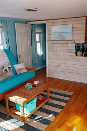 another shot of the living room, showing the coffee table, the entrance into the guest bedroom & whitewashed wall.