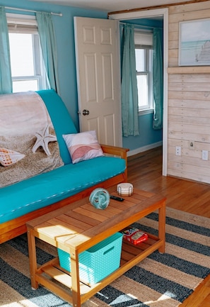 another shot of the living room, showing the coffee table, the entrance into the guest bedroom & whitewashed wall.