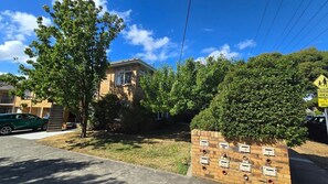 Quiet street with the first floor apartment visible on the corner between the trees