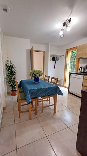 Espace repas pour 4 personnes, chaises à coussins, nappe pour votre séjour.