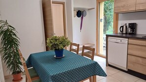 Espace repas pour 4 personnes, chaises à coussins, nappe pour votre séjour.