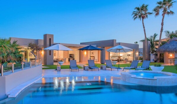 Expansive oceanview pool with cushioned loungers, perfect for relaxing under the sun.