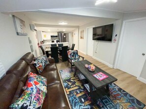 Unwind in our vibrant living room adorned with unique art, a sleek TV, and plush sofa, creating a cozy haven. A chic graffiti-covered bench adds style, making it the perfect space for relaxation and entertainment. 