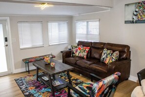 Unwind in our vibrant living room adorned with unique art, a sleek TV, and plush sofa, creating a cozy haven. A chic graffiti-covered bench adds style, making it the perfect space for relaxation and entertainment. 