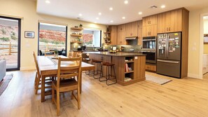 The spacious kitchen is a chef's dream, boasting top-of-the-line appliances, a breakfast bar for casual meals, plus a dining table for sit-down dinners for up to six.