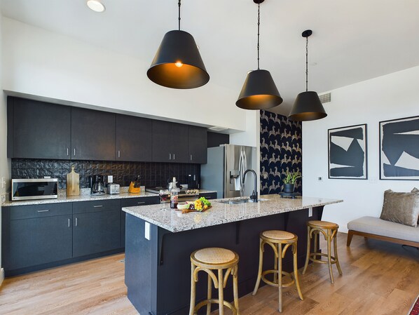 Fully equipped kitchen boasting stainless steel appliances and a kitchen island offering bar seating. The kitchen is completely stocked with all culinary essentials.