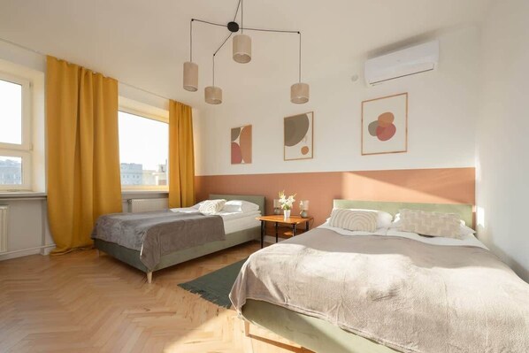 A stylish bedroom with a large bed, mustard-colored curtains, modern pendant lighting, and decorative wall art, creating a warm and inviting space.

