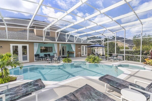 Gorgeous large tropical pool area with spa, surrounded by palm trees and shrubs.