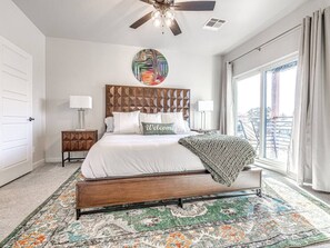 “Welcome to your serene master bedroom retreat! Our spacious room invites you to unwind & recharge. The neatly made bed, adorned with crisp white bedding and decorative pillows, whispers ‘relax.’ Let the natural light embrace you as you wake up daily. 