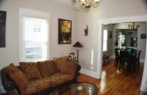 A welcoming dining space—hardwood floors, a cozy table, and chairs beneath a radiant chandelier. This room sets the stage for a comfortable and friendly stay, where every meal becomes a delightful gathering in a warm and inviting setting.