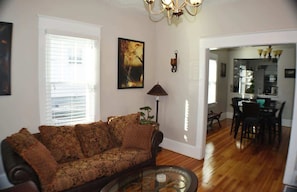 A welcoming dining space—hardwood floors, a cozy table, and chairs beneath a radiant chandelier. This room sets the stage for a comfortable and friendly stay, where every meal becomes a delightful gathering in a warm and inviting setting.