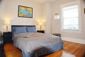 Bathed in gentle sunlight, this bedroom oasis features a cozy bed beside a window, adorned with a captivating painting. A bedside lamp casts a soft glow, creating a serene retreat where comfort and artistry harmoniously converge.