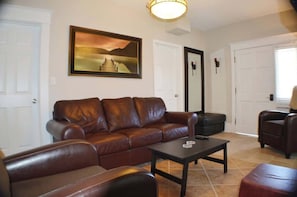Luxury meets comfort in this living room adorned with rich brown leather furniture. Above the sumptuous couch, a captivating painting adds artistic flair. The central coffee table ties the ensemble.