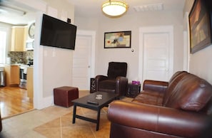 Bask in comfort within this well-appointed living room. A curated ensemble of furniture embraces warmth around a fireplace. A wall-mounted flat-screen TV above completes the cozy haven, inviting relaxation.