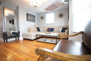 Welcome to an inviting living space adorned with thoughtfully arranged furniture. A large mirror above the plush couch adds depth and elegance. The coffee table rests on gleaming hardwood floors, creating a harmonious blend of comfort and style in this co