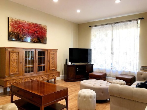 A tastefully appointed living room, brimming with comfortable furniture, accentuated by a flat-screen TV elegantly mounted on the wall above a finely crafted wooden entertainment center, offering both style and function.