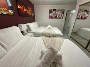 This cozy bedroom features two comfortable beds with fresh white linens, a wall-mounted TV, and stylish decor, creating a relaxing space for your stay in the heart of Las Vegas.