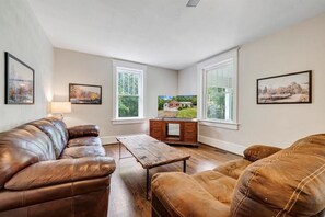 Family room with plush leather couches, rustic table, and Smart TV