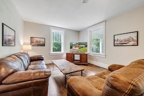 Family room with plush leather couches, rustic table, and Smart TV