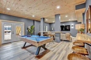 Recreational room with pool table, shuffleboard, and second living room with ultra HD smart TV.  Walk right out to the hot tub and firepit.