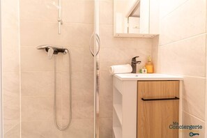 Salle d'eau avec douche, sèche-cheveux, et toilettes