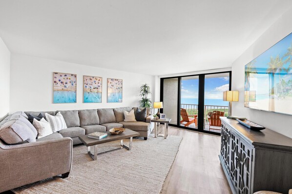 Spacious living area with sofa bed sectional and Samsung Smart TV, balcony