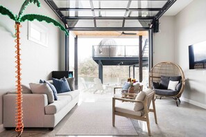 This lower level living room has a roll up garage door that leads straight to the lake.  Fun seating, 65" smart TV, bar and fridge - these are all the ingredients you need to get the party started!