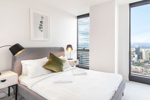 The light and airy second bedroom includes a queen bed with side tables and reading lamps, while both bedrooms include mirrored built-in robes. 
