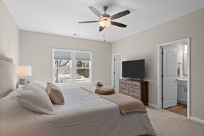 Master suite with king bed, walk-in closet, private ensuite, desk, and smart TV.