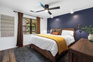 Second bedroom at front of condo w/king bed, dresser, blackout curtains, & fan.