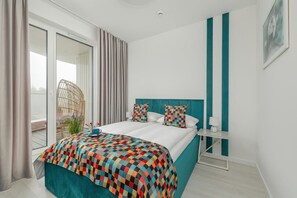 A stylish bedroom with a turquoise accent wall, a patterned bedspread, and access to a private balcony.

