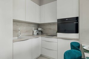 A sleek kitchen with white cabinetry, built-in appliances, and a gray backsplash, blending elegance with functionality.